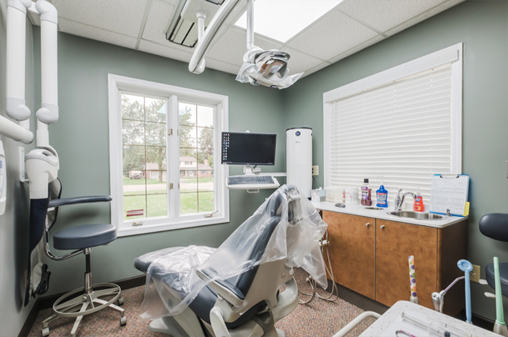 A modern dental office with chairs, equipment, and a window.