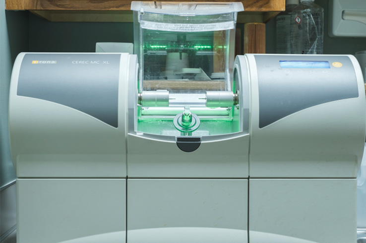 The image shows a piece of industrial equipment with various panels and buttons, likely used for printing or processing documents, situated on a table or countertop with a green tint.