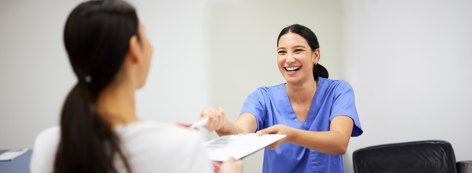 A well-lit reception area with a desk, computer monitor, and potted plant.