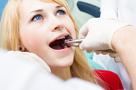 A young woman receiving dental care with a dental professional performing the procedure.