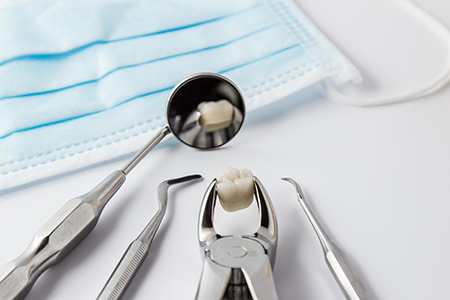 The image shows a collection of dental instruments, including a toothbrush with toothpaste on it, placed on a blue cloth, which appears to be a sterilization wrap commonly used in dental practices.