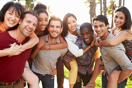 The image shows a group of people posing together with smiles on their faces, embracing each other in a celebratory manner, suggesting a happy gathering or event.