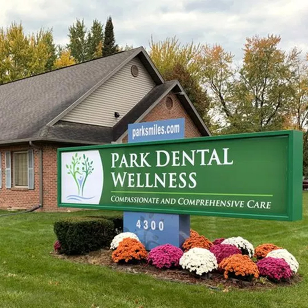 The image shows a sign for Park Dental Wellness with a tree graphic and the message Compassionate and comprehensive care.